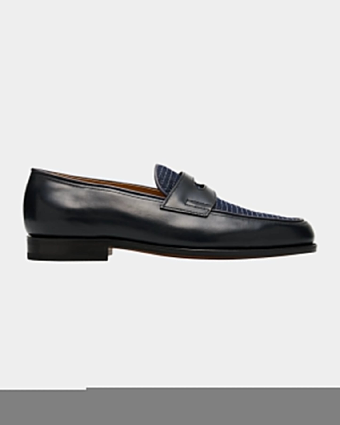 Black leather loafer with blue textured detail on a light gray background
