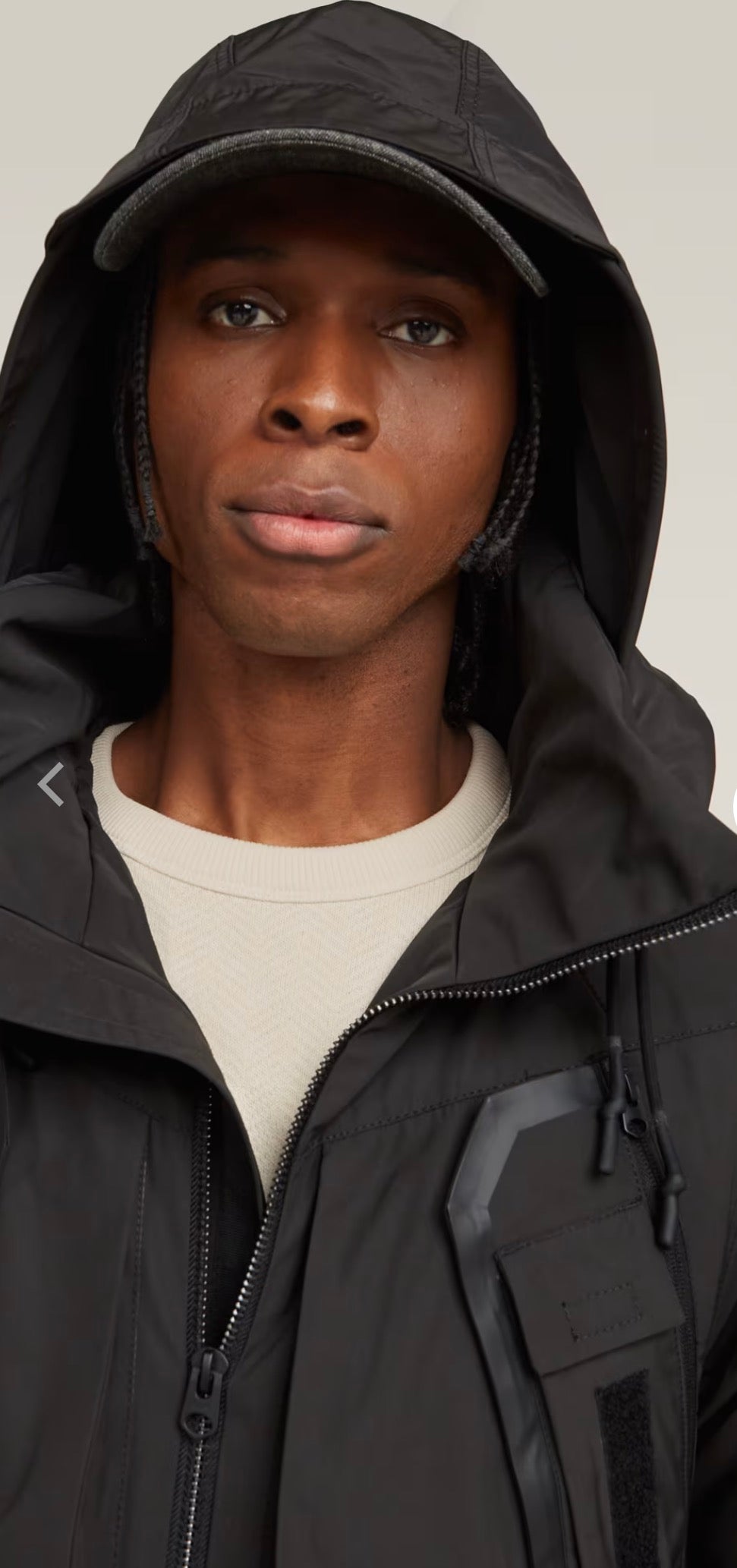 Person wearing a black hooded jacket against a plain background