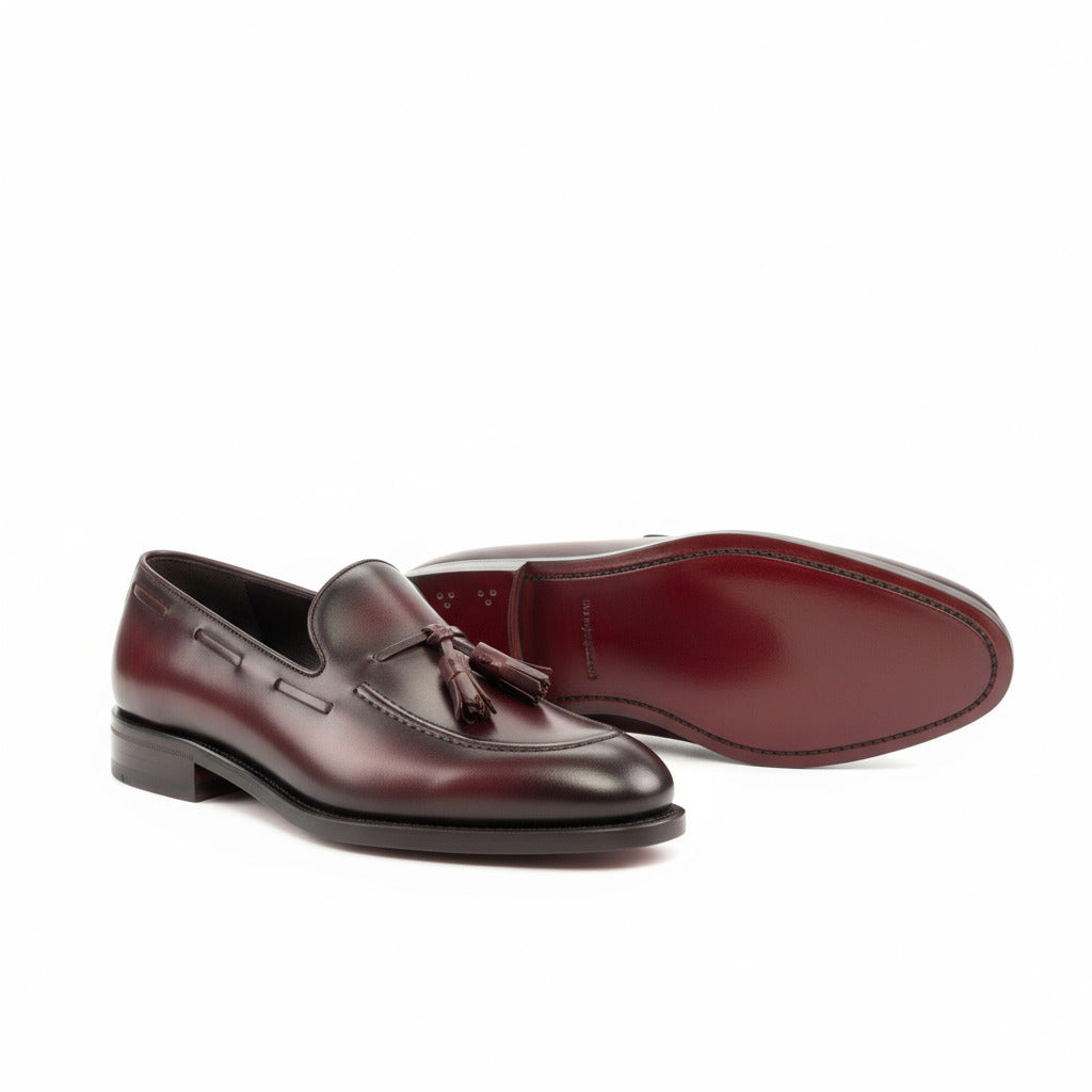 Pair of brown leather loafers with tassels on a white background