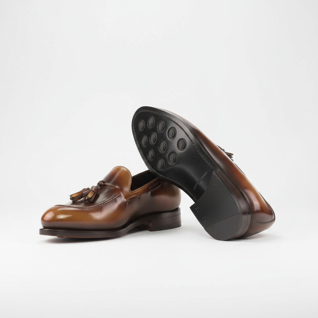 Brown leather loafer with a red sole on a white background