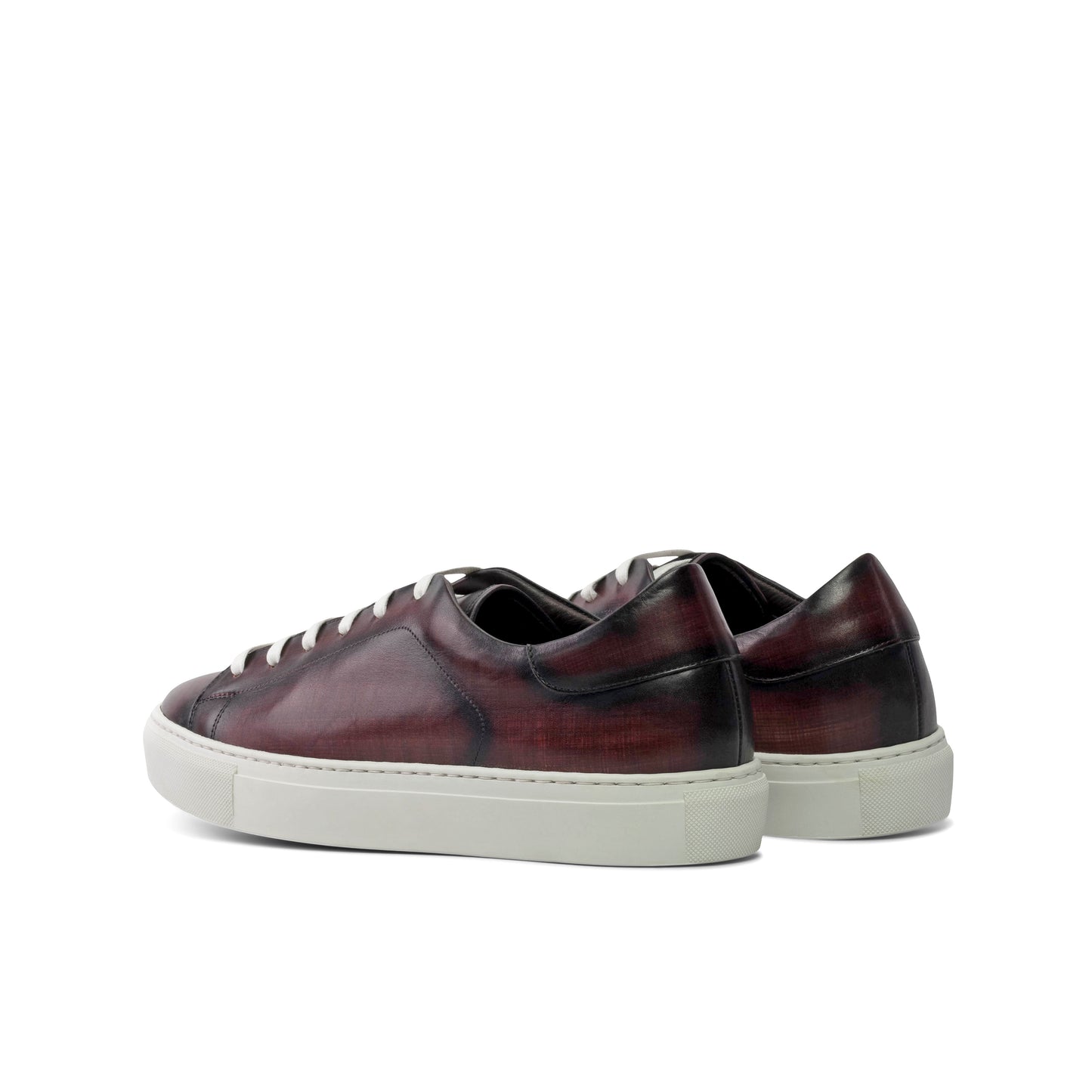 Pair of maroon sneakers with white soles on a white background