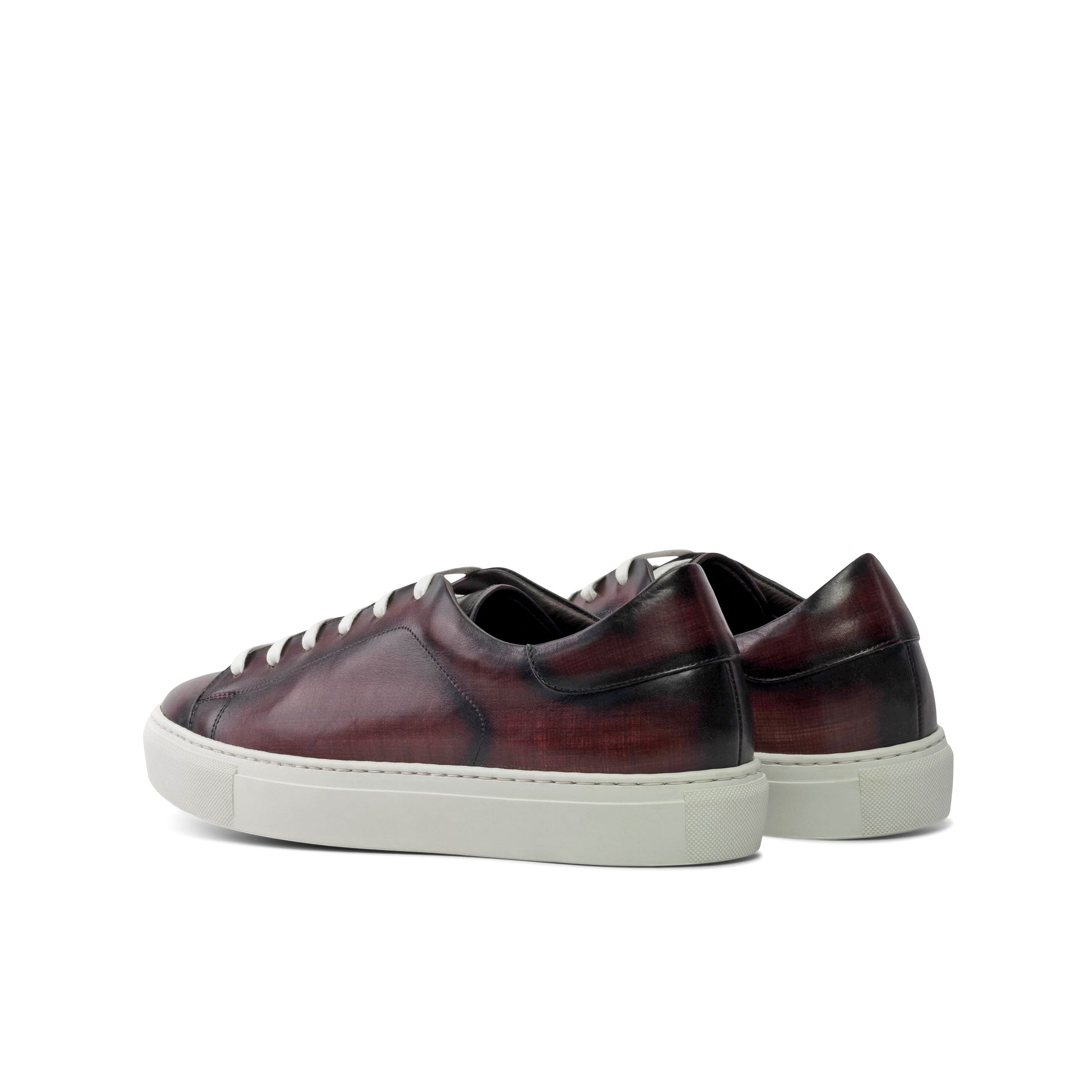 Pair of maroon sneakers with white soles on a white background
