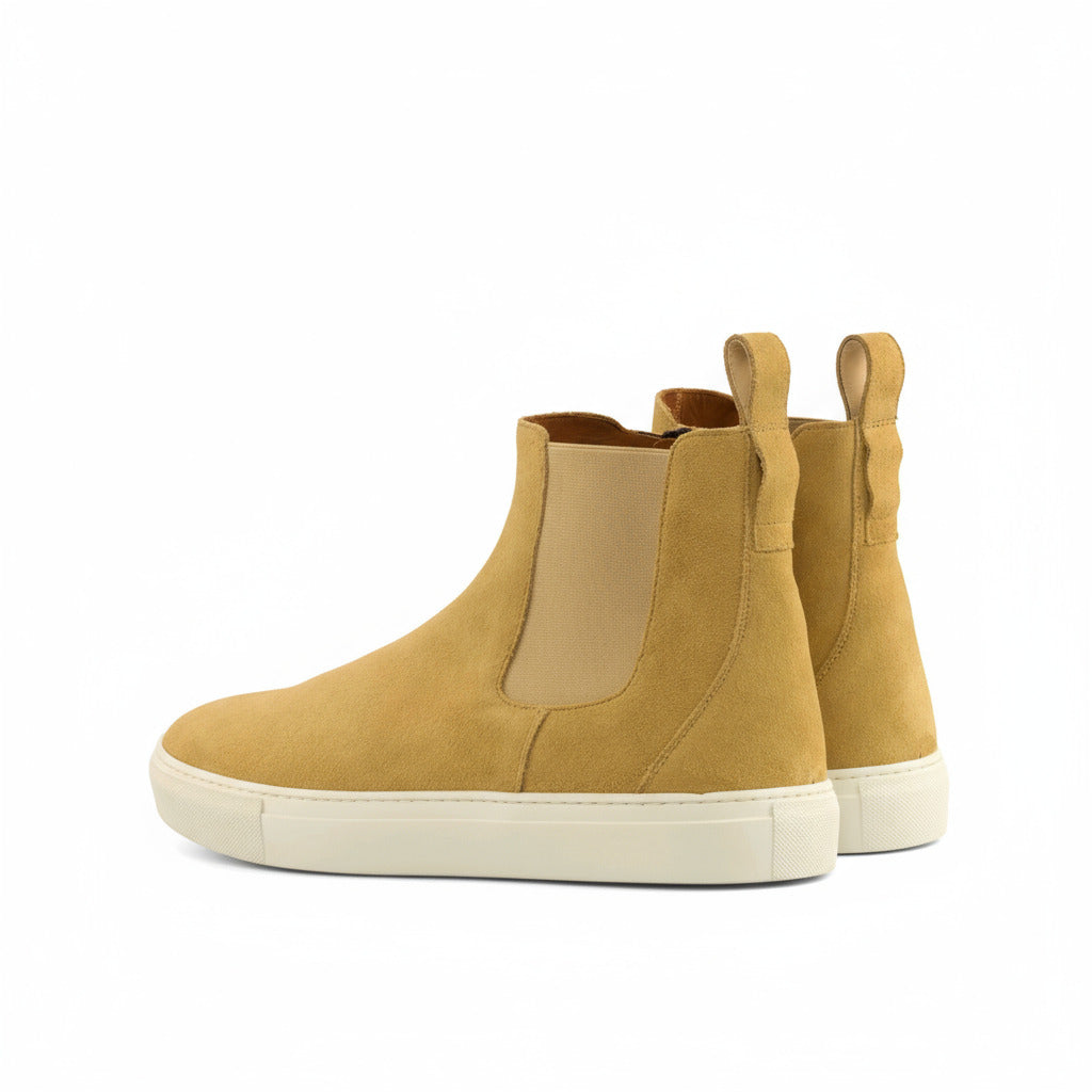 Pair of mustard yellow Chelsea boots on a white background