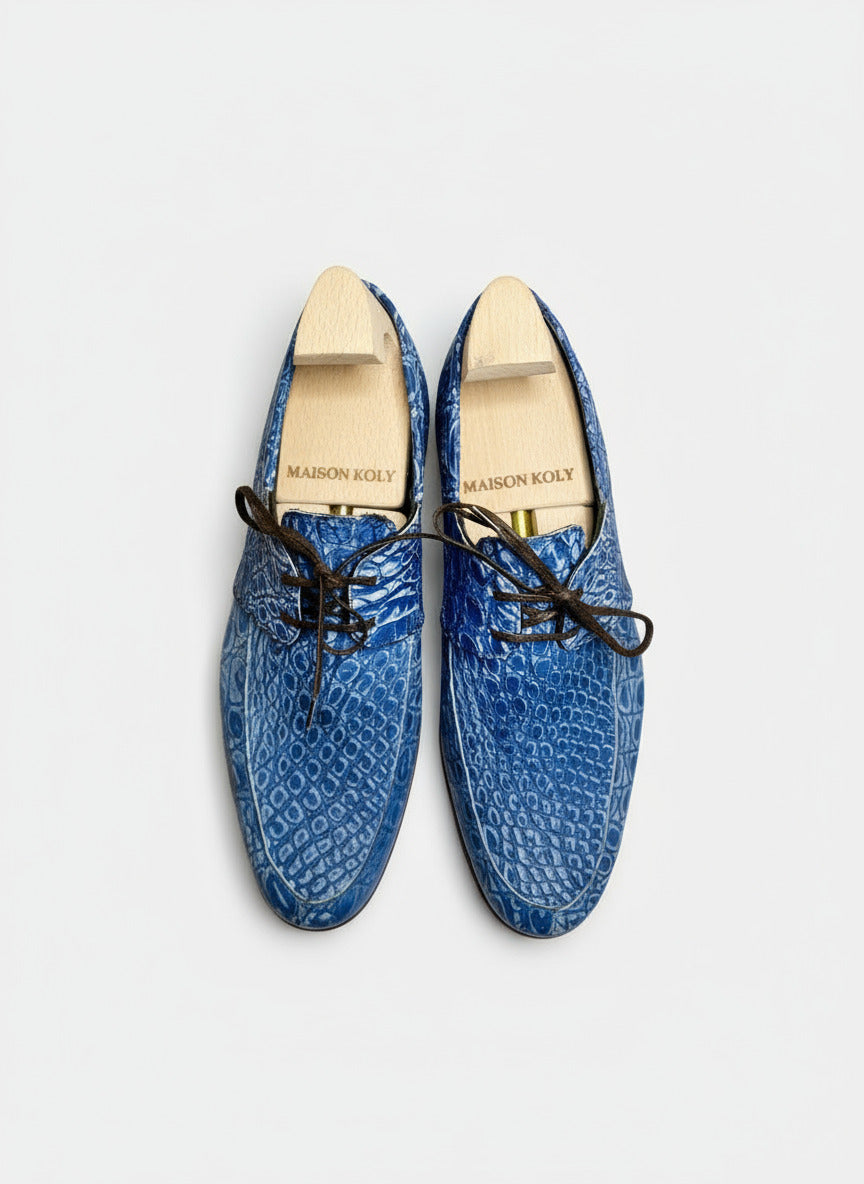 Blue textured shoes with black laces on a white background, featuring 'Maison Koly' branding.