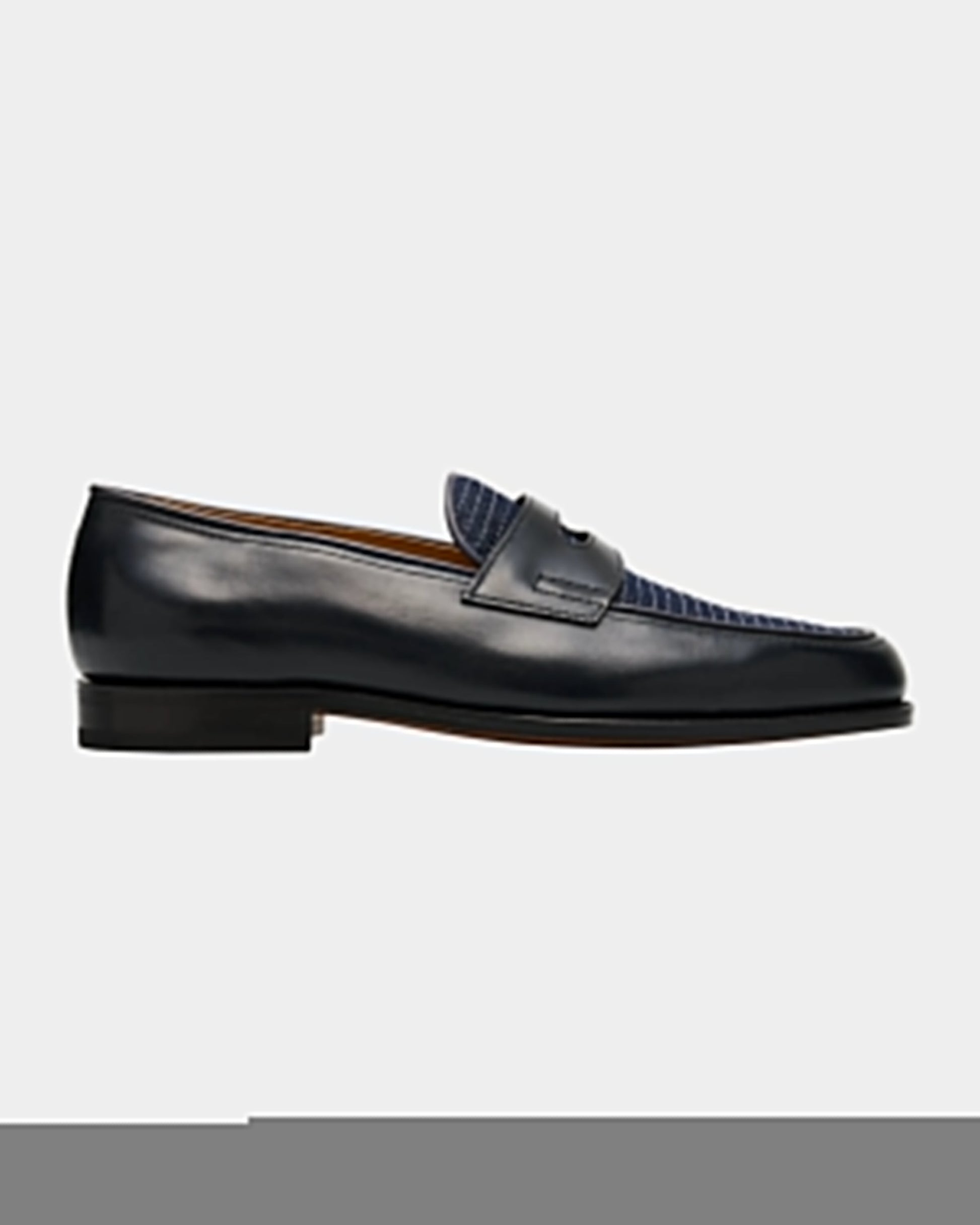 Black leather loafer with blue textured detail on a light gray background